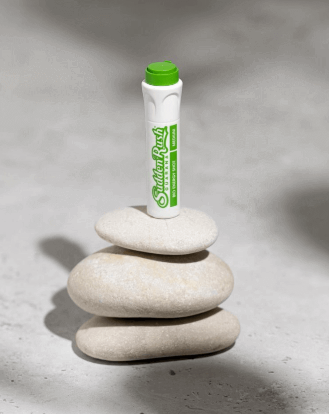 Green Guarana Energy Shot by Sudden Rush on top of stacked white stones