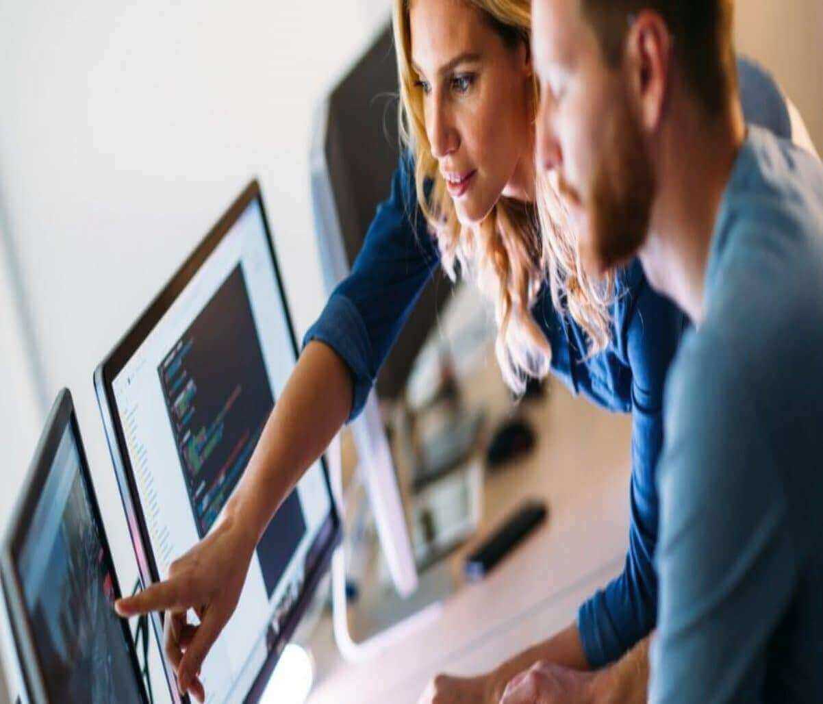 Colleagues collaborating on programming code at a computer workstation.